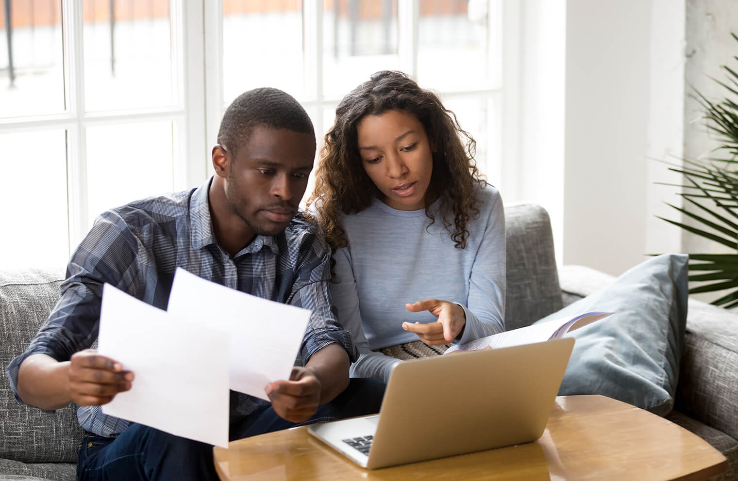 Picture of a couple sitting at a desk with a laptop reviewing paperwork.