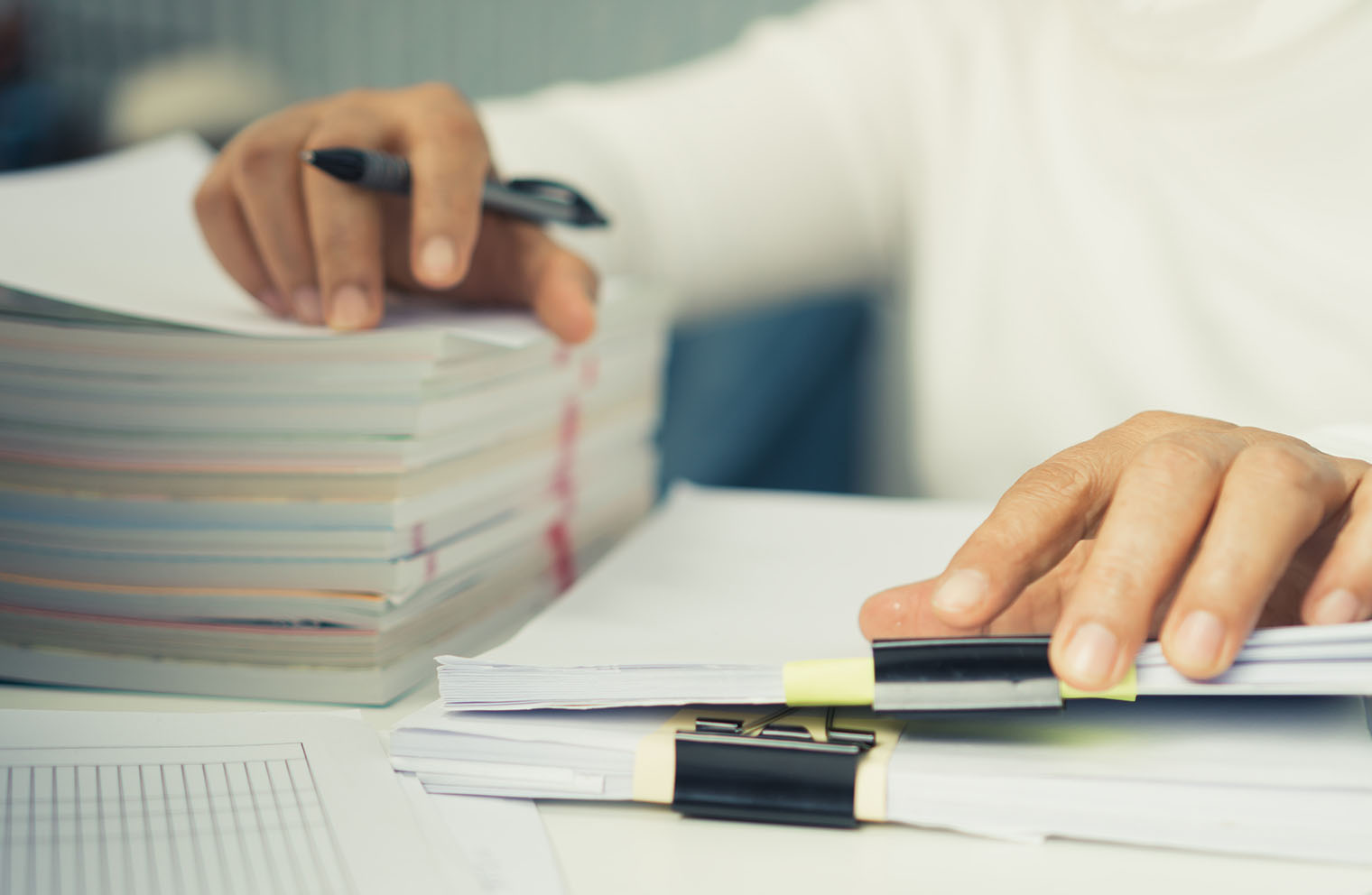Image of worker at desk with large stacks of paper
