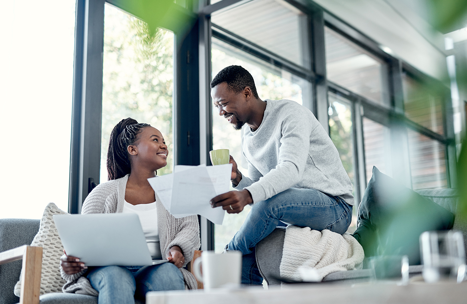 A husband and wife sit together with a laptop and paperwork to compare personal health plans.