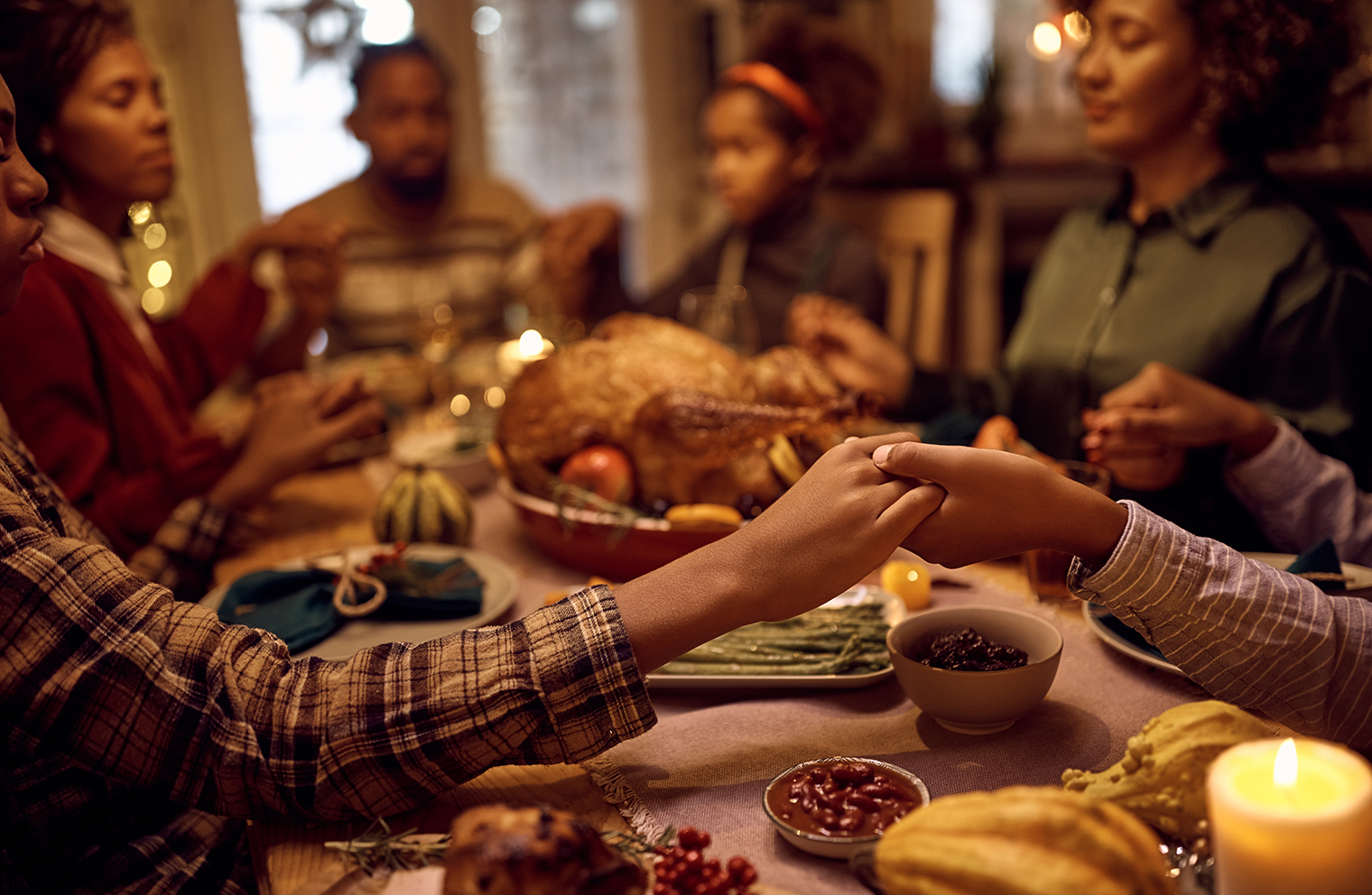 A family holds hands and prays over a healthy holiday meal.