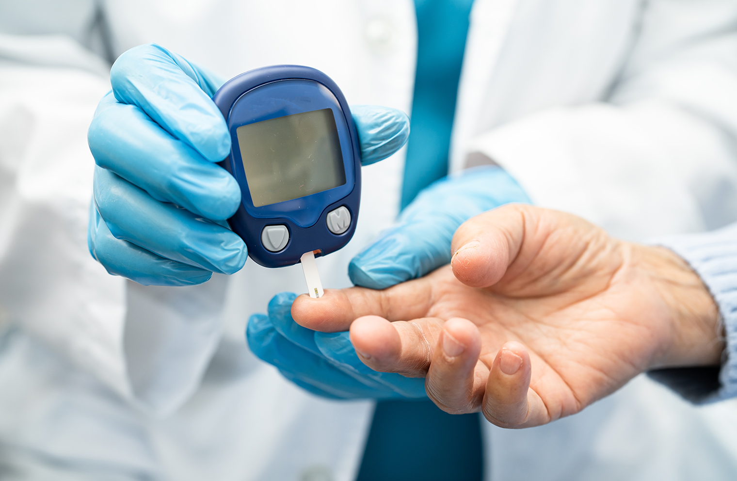 A patient with diabetes gets their fingertip poked with a blood glucose meter.