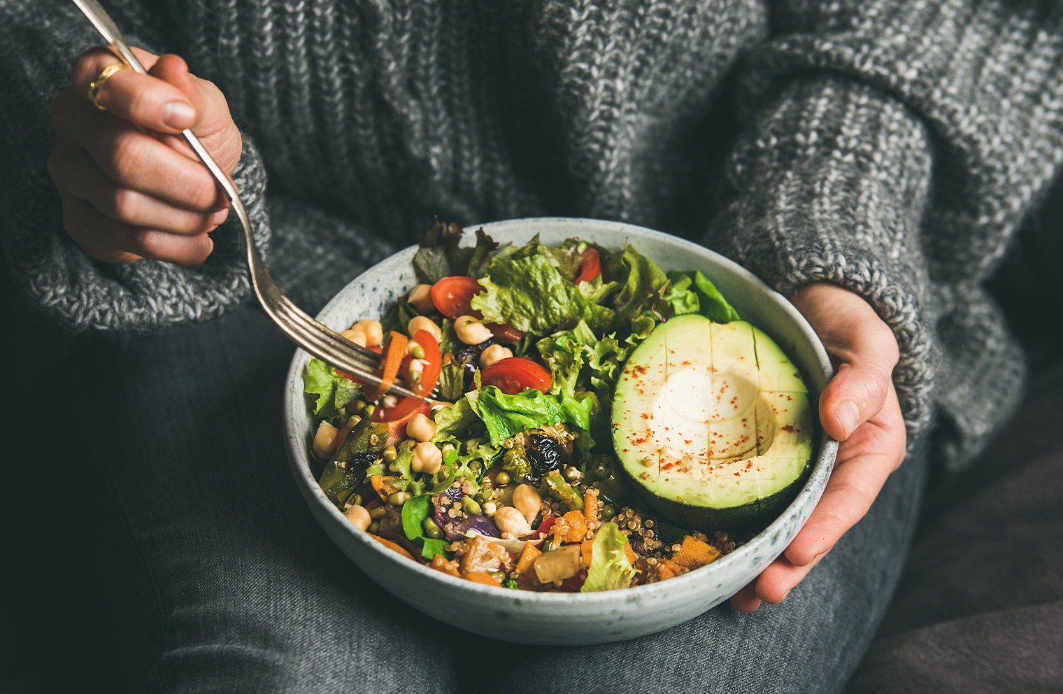 A woman eats a nutritious salad with a variety of healthy foods. 