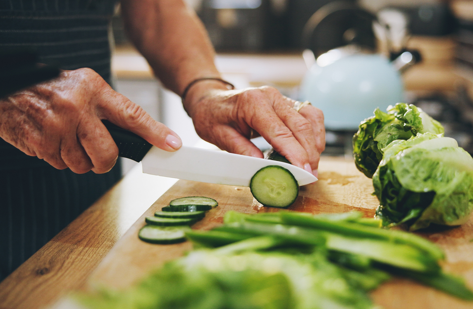 Someone slices cucumbers on a cutting board to meal prep.