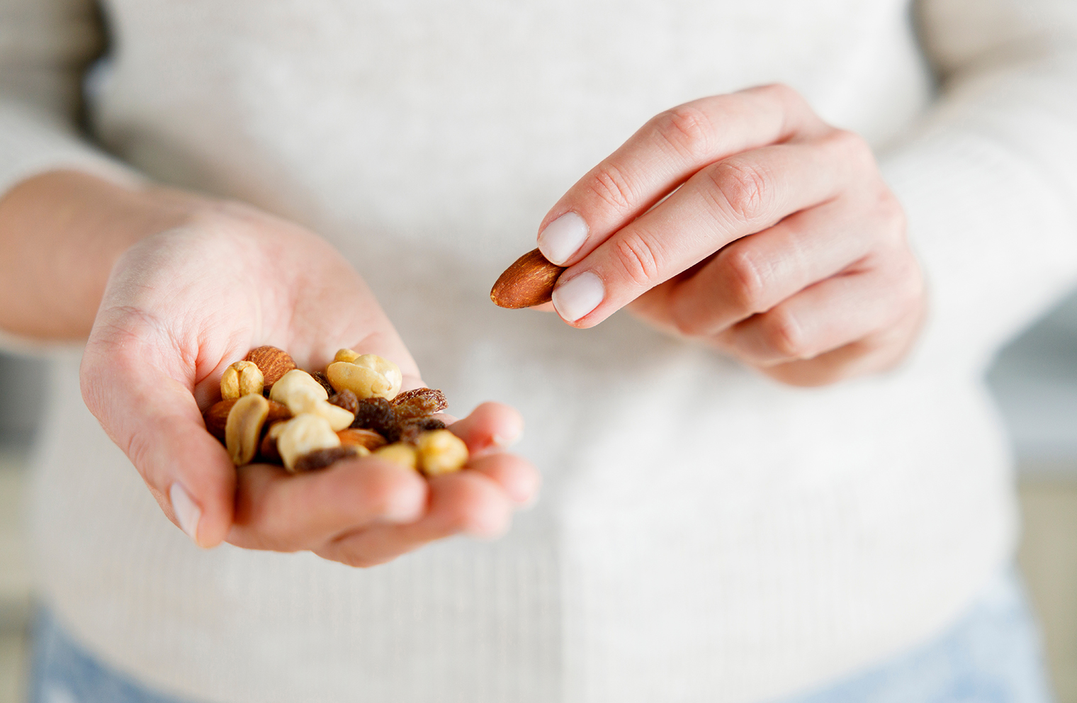 A woman holds a handful of trail mix for a healthy snack. 