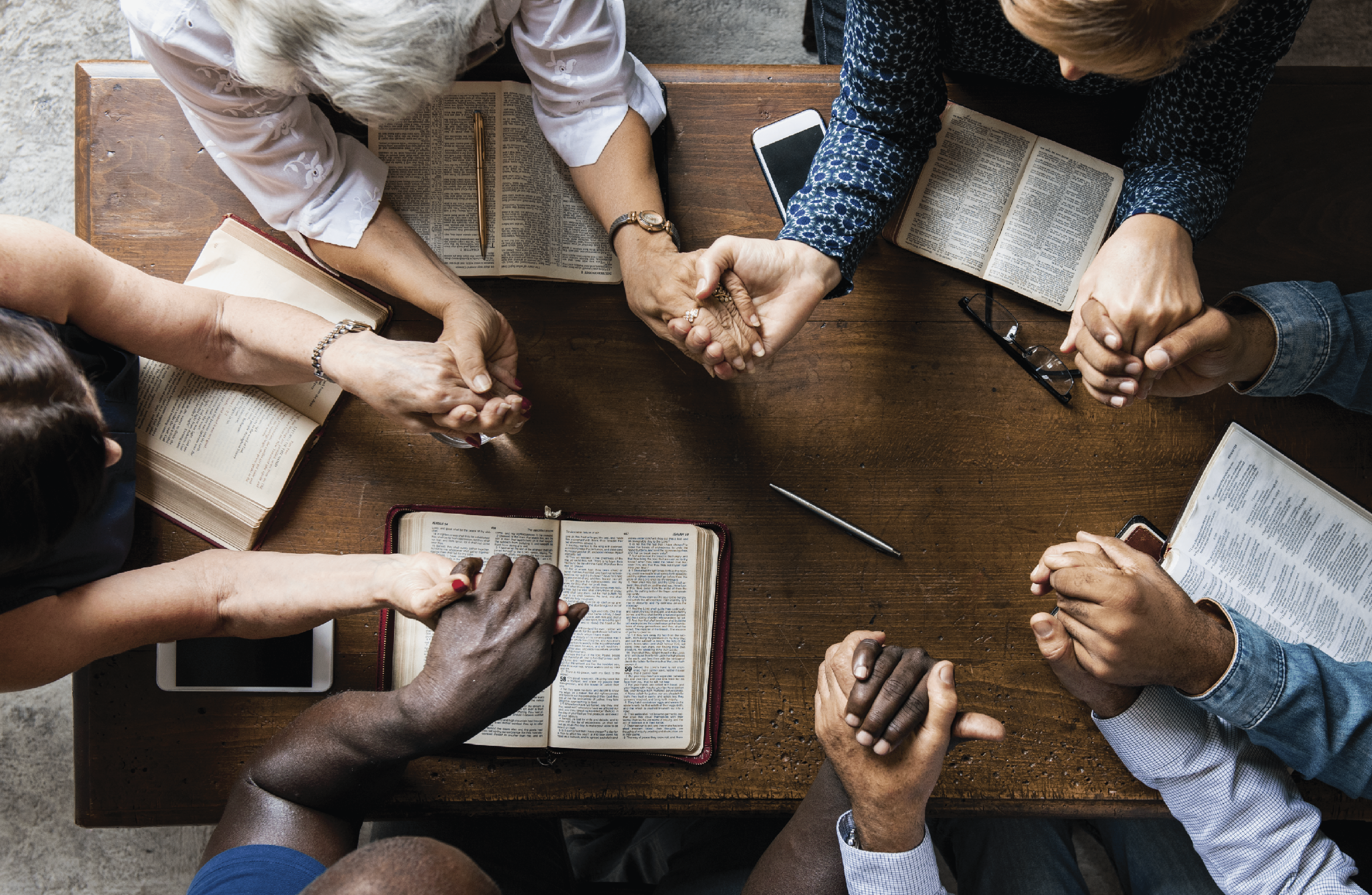 A group of church planters hold hands to pray about health care coverage. 