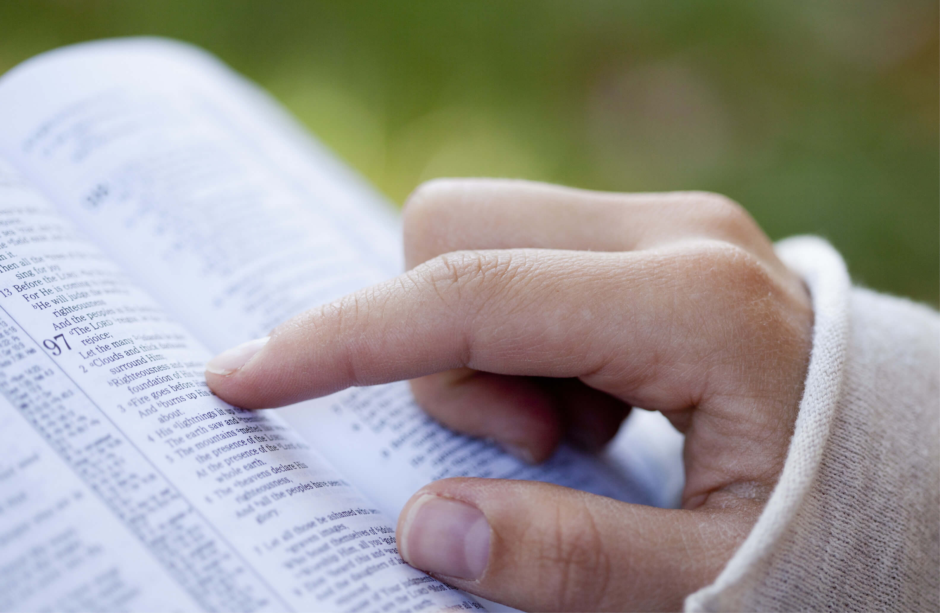 finger pointing to a bible verse in open bible