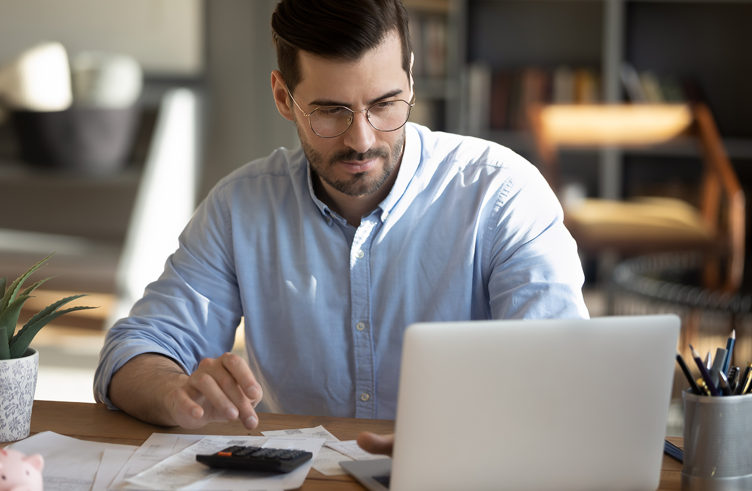 A man budgeting at a table with a calculator and laptop