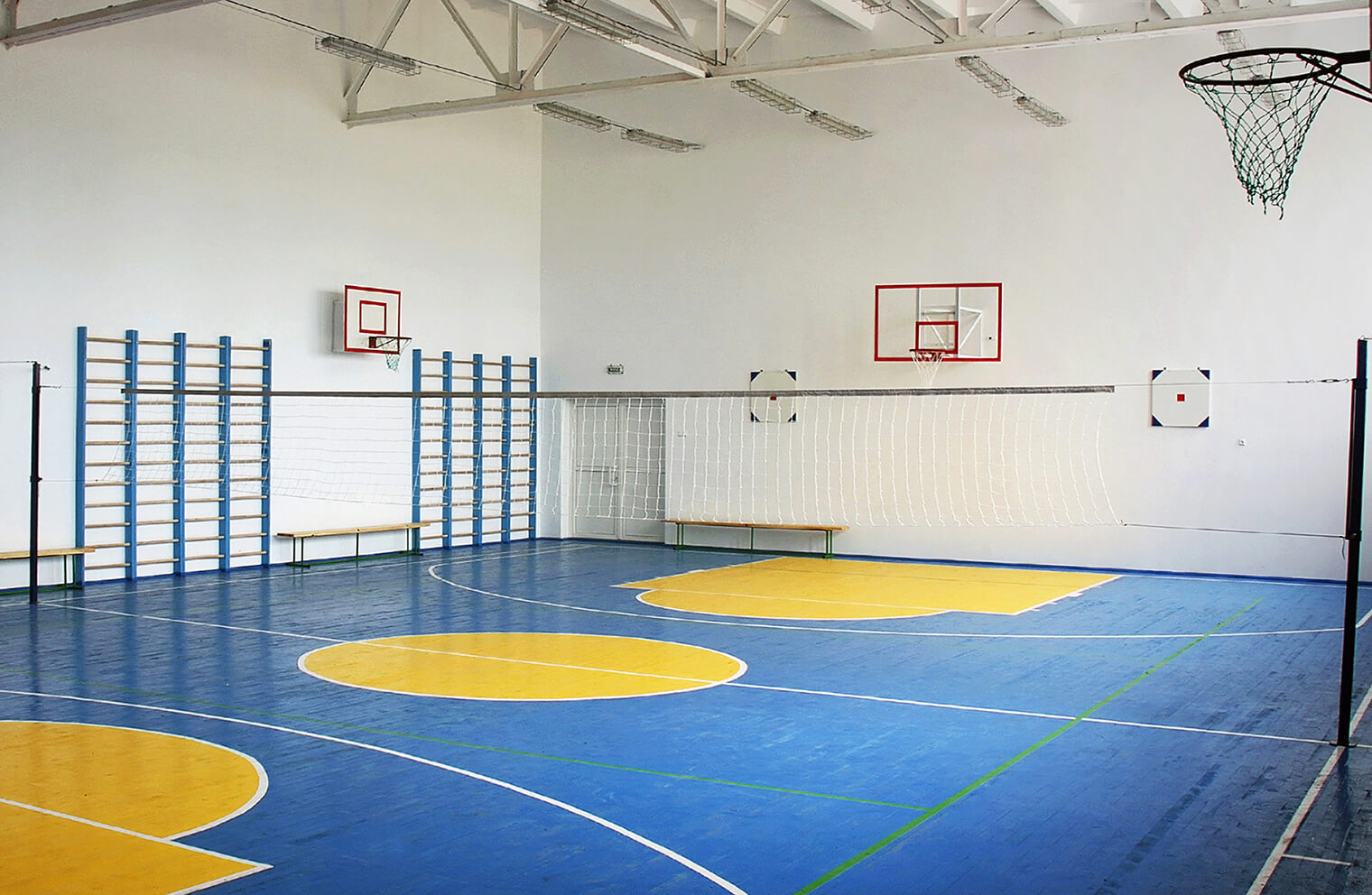 Picture of empty basketball gym with blue court and golden center court and lanes.