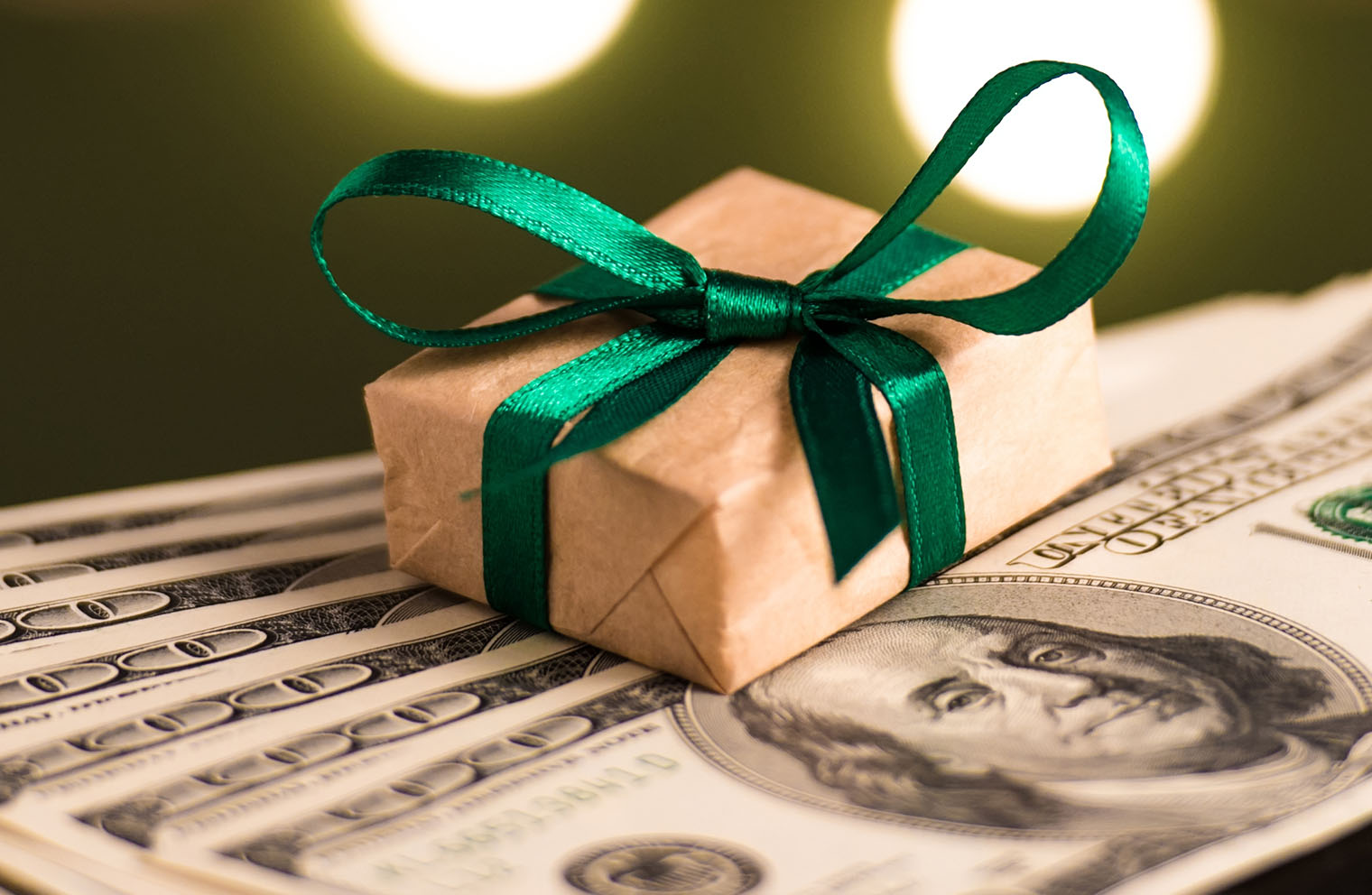 Image of small gift box sitting on top of several hundred dollar bills