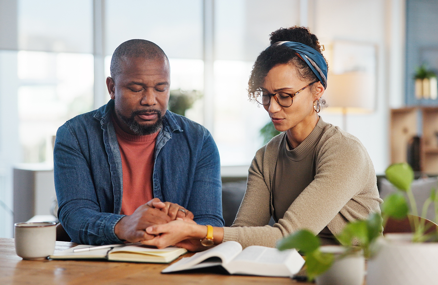 A man and a woman praying together over a Bible