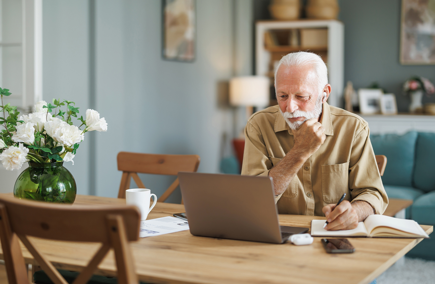 An older man sitting at a table with a laptop planning his retirement