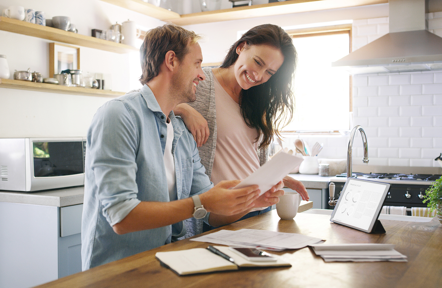 A young couple at a kitchen counter budgeting together