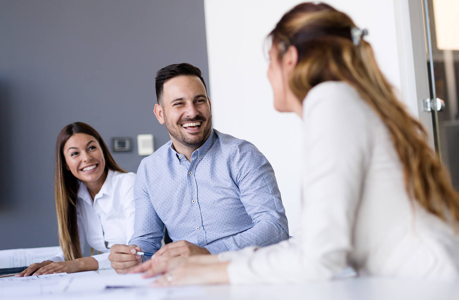 Picture of three people in a conference room smiling at each other.